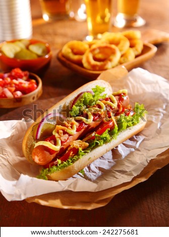 Traditional hot dog with a smoked frankfurter on a fresh roll garnished with mustard and ketchup and served with lettuce, tomato and onion