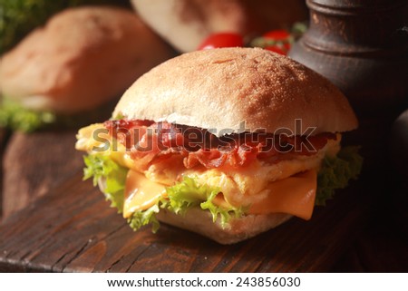 Close up Fresh Burger with Egg, Cheese and Bacon, Added with Lettuce, on Top of Wooden Table.