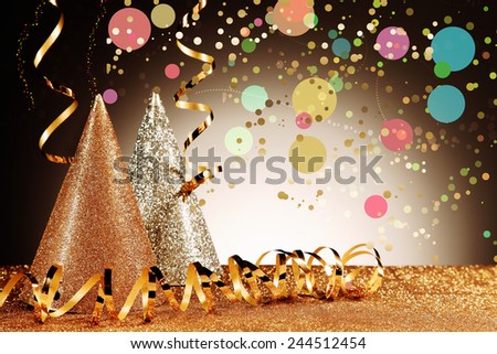 Close up Glittery Carnival Cone Hats and Gold Streamers with Confetti Effect on Glittery Table in Front Gradient Brown Background