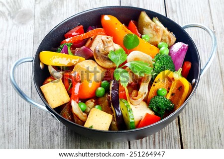 Healthy snack of assorted farm fresh roast vegetables and tofu or soybean curd in a bowl on a rustic grey wooden table