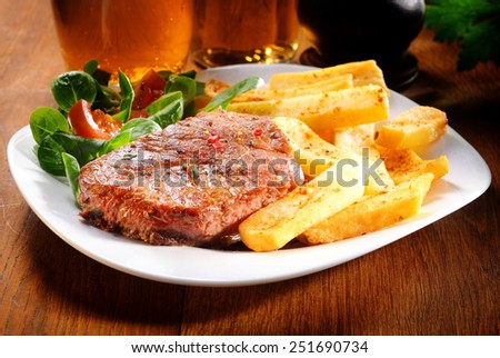 Gourmet Healthy Grilled Beef and Potato French Fries on White Plate with Herbs and Veggies. Placed on Wooden Table.