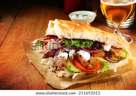 Close up Burger Slice with Grilled Meat Doner and Veggies on Brown Paper, Placed on Wooden Table.