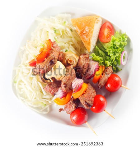 Close up Aerial Shot of Appetizing Kebabs on White Plate with a Slice of Bread and Fresh Veggies. Isolated on White Background.