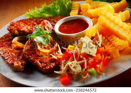 Close up Gourmet Grilled Meat with Fries, Veggies and Tomato Sauce on White Plate