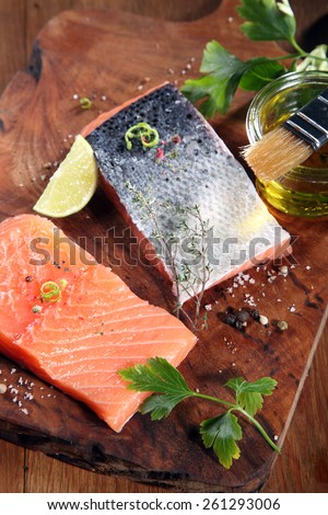 Close up Raw Salmon Fish Meat on Wooden Cutting Board with Herbs and Spices and Olive Oil