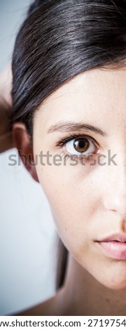 Close up Portrait of a Gorgeous Woman Half Face, Holding Back her Hair While Looking at the Camera