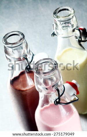 Creamy healthy blended milkshakes or smoothies served in glass bottles at a party, bar or restaurant with a variety of flavours, close up of the open necks of the bottles