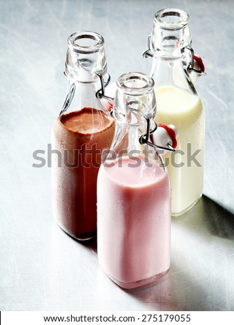 Still Life of Healthy Blended Smoothie Shakes in Three Glass Bottles with Open Tops on Shiny Metal Surface
