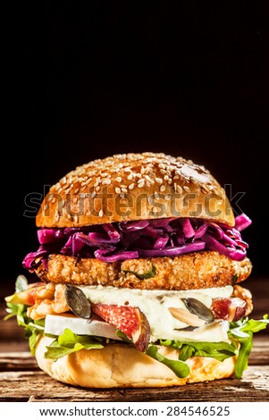 Close Up of Gourmet Burger Piled with Fresh Toppings on Whole Grain Bun, on Black Background with Copy Space
