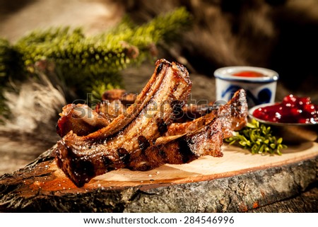 Appetizing BBQ Boar Spare Ribs with Grill Marks Served on Rustic Wood Plank Accompanied by Sauces