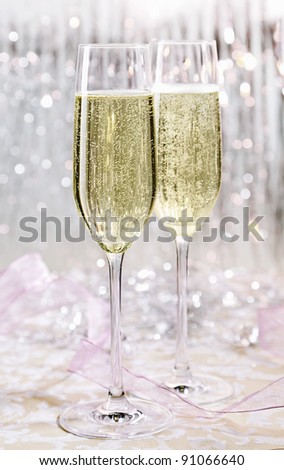 Two elegant flutes of sparkling white champagne with lots of bubbles on festive background, celebration concept.