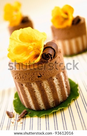 Rich gourmet chocolate desserts of a striped cake base topped with chocolate and mousse and a decorative yellow flower