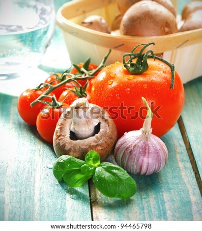 Fresh cooking ingredients for pasta including mushroom, garlic, tomato and fresh herbs on rustic wooden boards.
