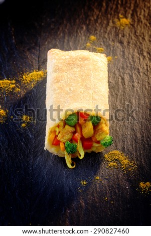 High Angle View of Half a Crisp Fried Vegetable Spring Roll on Dark Textured Surface Dusted with Golden Spice Powder