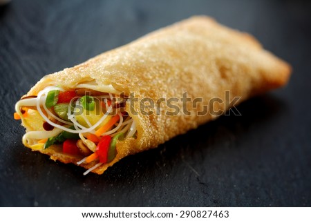 Close Up of Crisp Fried Spring Roll Filled with Fresh Vegetables and Sprouts on Dark Surface