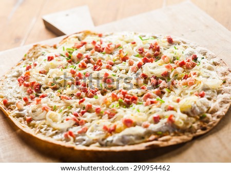 Close Up of Rustic Thin Crust tarte flambee Pizza Topped with Fresh Ingredients on Wooden Cutting Board
