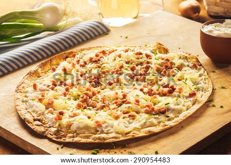 Close Up of Rustic Thin Crust French Pizza on Wooden Cutting Board Surrounded by Fresh Ingredients