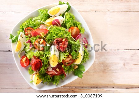 High Angle View of a Nutritious Vegetable Salad with Boiled Egg Slices, Served on a White Plate on Top of a Wooden Table