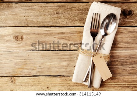 High Angle View of Spoon and Fork Tied on a White Napkin with Empty Tag, Placed on Wooden Table with Copy Space.