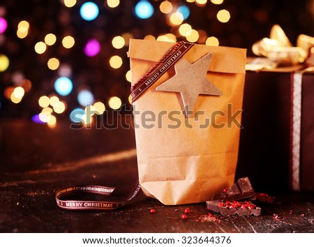 Rustic Christmas package of a brown paper packet decorated with star against a colorful bokeh of sparkling lights celebrating the festive season