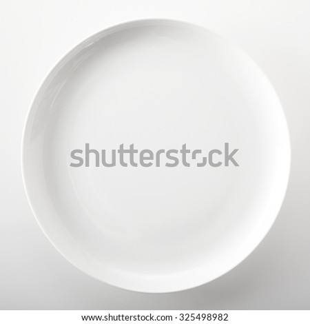 Empty plain white round generic dinner plate with place for placement of food or a recipe viewed close up overhead over a white background in square format