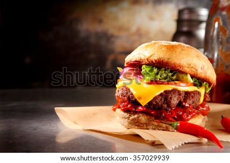 Red hot chili cheeseburger with a spicy chilli pepper sauce and melting cheese over a juicy beef patty on a crusty bun served on brown paper, with copyspace