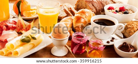 Breakfast feast with egg, meat, bread, coffee and juice