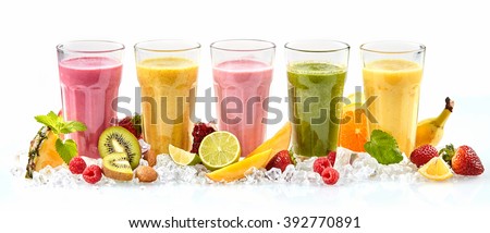 Row of five tropical fruit drinks in tall glasses next to strawberries raspberries and cut lime mango and kiwi standing in a bed of crushed ice