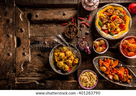 High Angle View of Traditional Tajine Dishes and Fresh Ingredients Arranged on Rustic Wooden Table Made from Old Door - Still Life with Copy Space