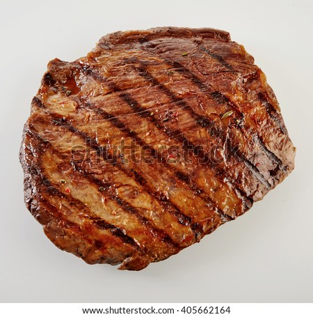 Juicy thick medallion of lean flank beef steak marinated and grilled over a summer BBQ viewed close up from above over white