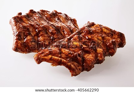 Two portions of delicious spicy marinated spare ribs barbecued over the grill over a white background