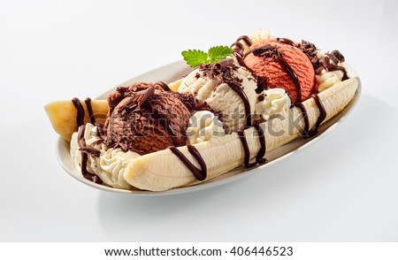 Delicious sweet banana split ice cream dessert with garnishment of chocolate syrup, and peppermint leaf on top in bowl on table