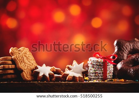 Christmas cookies and biscuits festive background arranged on a rustic wooden table with spicy speculoos, starsand chocolate confections, low angle with colorful party bokeh and copy space