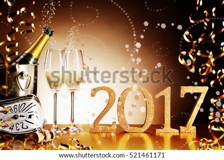 Celebrating 2017 New Years Eve with a festive still life of sparkling champagne with escaping bubbles, gold party streamers and a glittering golden date for a luxury holiday background with copy space