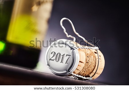 Close up view at angle of the year 2017 on end of cork and metal cap. Wine bottle of focus in background.