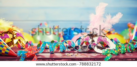 Colourful carnival panoramic banner with a jumble of party balloons, streamers, conical hats and confetti on a wooden table with copy space