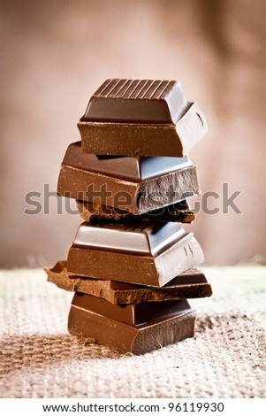 Tower composed of pieces of staple chocolate on a linen background for chocolate and cocoa concepts.