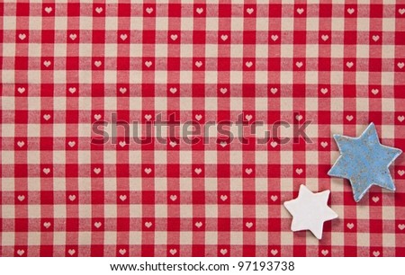 Background of two silver stars lying on colourful fresh red checked fabric with tiny hearts