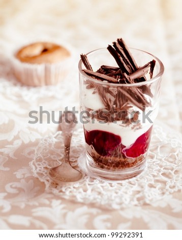 Gourmet fruit and cream parfait topped with chocolate shavings and served in a clear glass on a decorative doily
