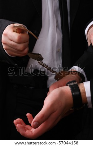 business man being arrested, only the hands of the police detective and business man are visible