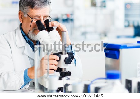 senior male researcher carrying out scientific research in a lab using a microscope (shallow DOF; color toned image)