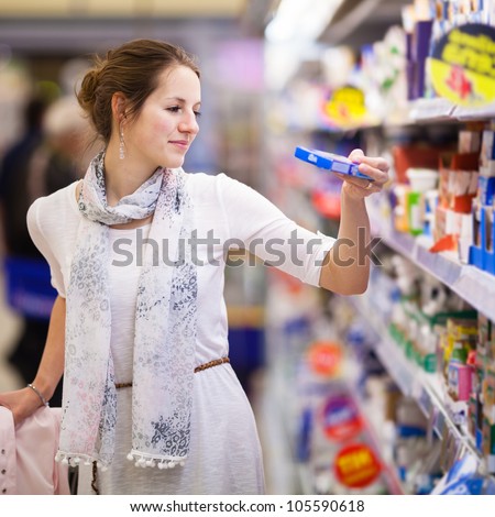 Beautiful young woman shopping for diary products at a grocery store/supermarket (color toned image)