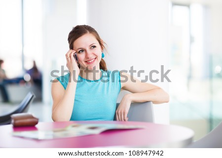 Pretty young woman using her mobile phone/speaking on the phone in a public area (shallow DOF; color toned image)