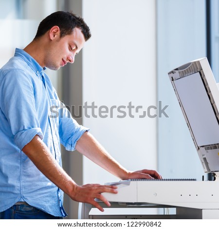 Handsome  young man using a copy machine (shallow DOF; color toned image)
