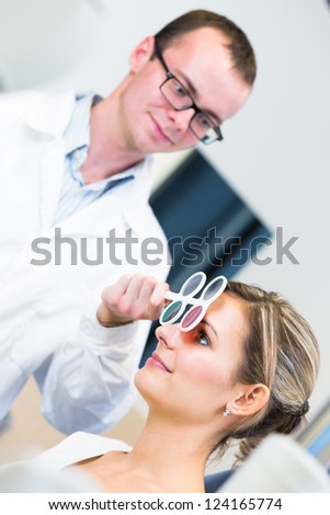 Optometry concept - pretty young woman having her eyes examined by an eye doctor/optometrist (color toned image; shallow DOF)