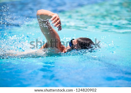 Young man swimming the front crawl in a pool