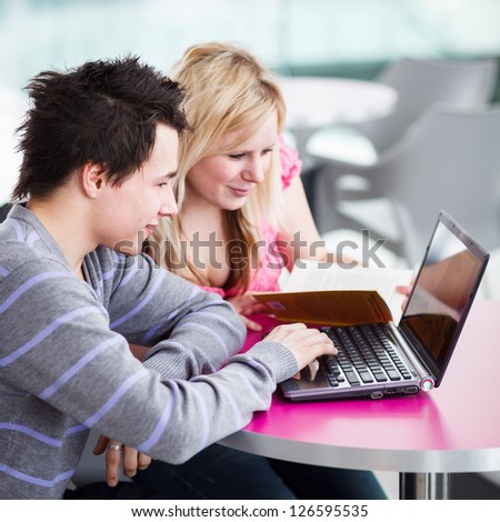 Two college students having fun studying together, using a laptop computer on campus, between classes (shallow DOF, color toned image)