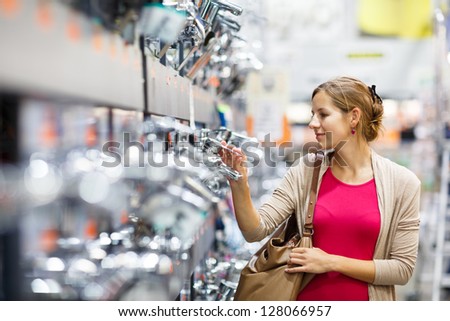 Pretty young woman choosing a bathroom/kitchen tap in a home furnishings retail store