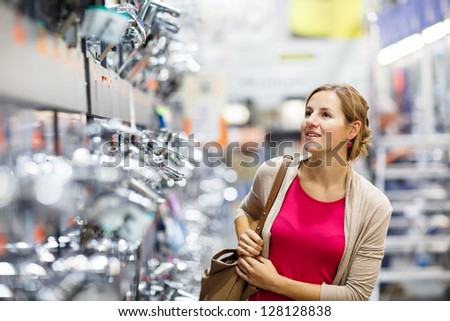 Pretty young woman choosing a bathroom/kitchen tap in a home furnishings retail store