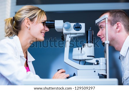 Optometry Concept - Handsome Young Man Having His Eyes Examined By An Eye Doctor (Color Toned Image; Shallow Dof)